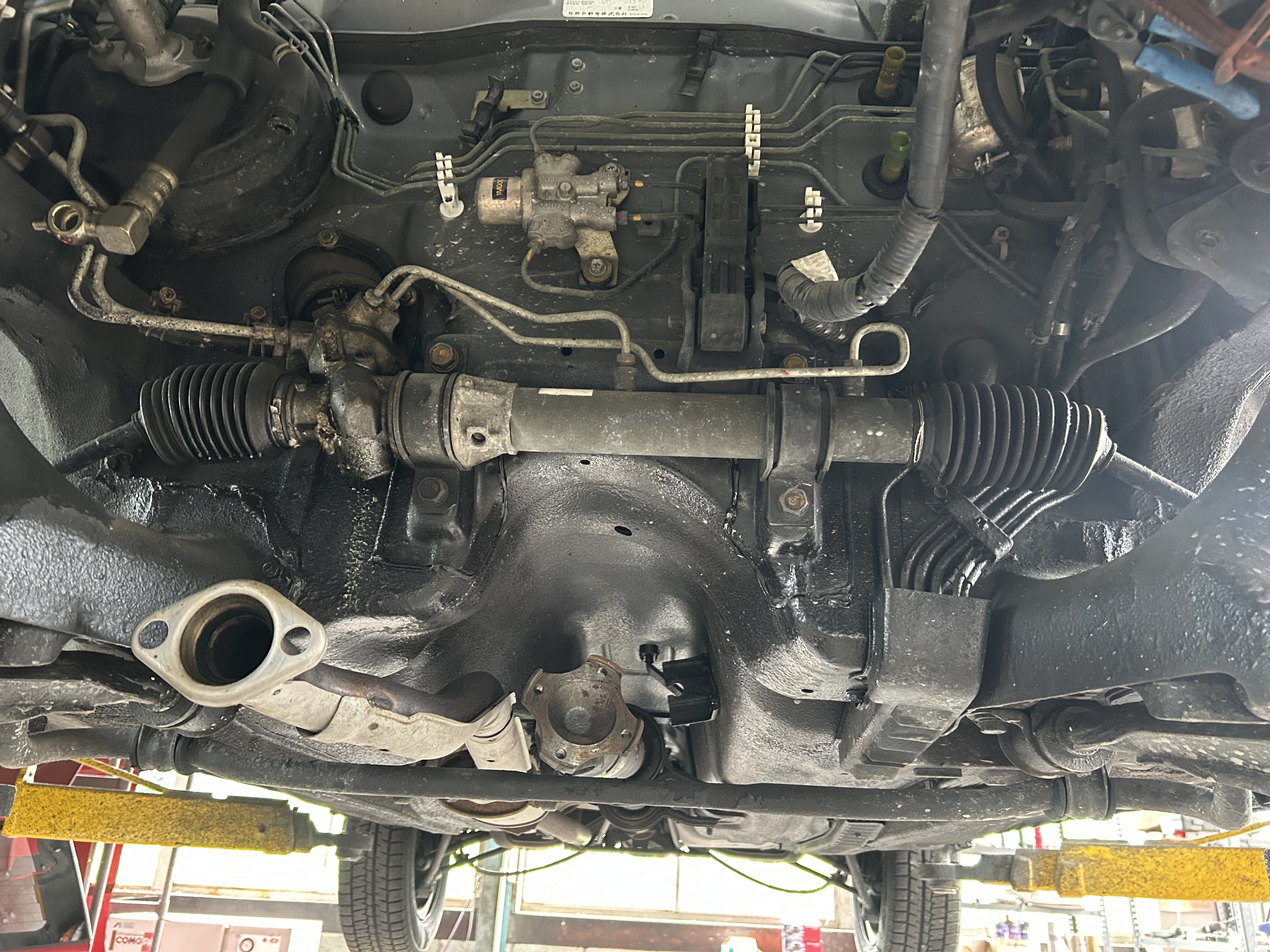 The original power steering rack installed on the vehicle before removal.