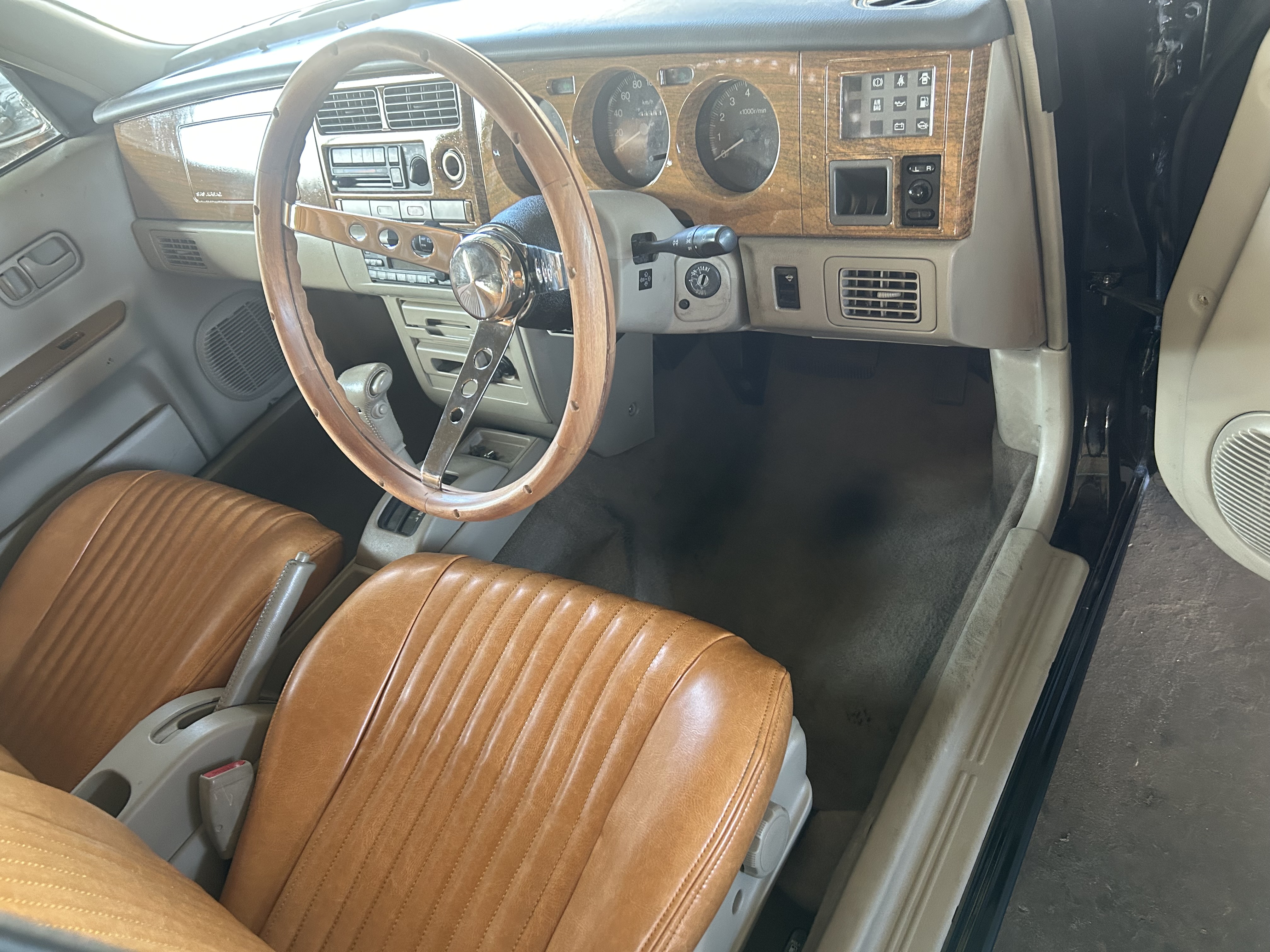 Camel-brown upholstery, wood-grain trim and a wood steering wheel create a warm, classic cabin.
