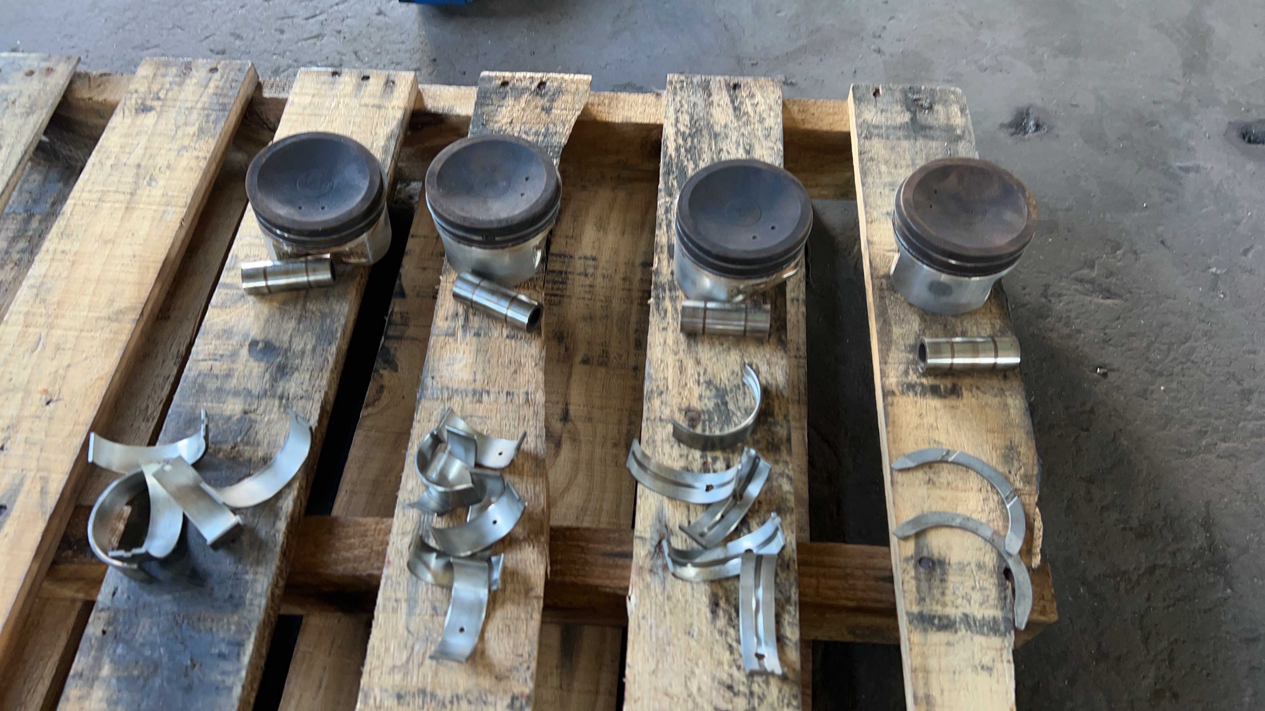 The pistons, wrist pins and removed bearing shells were kept in order for inspection.